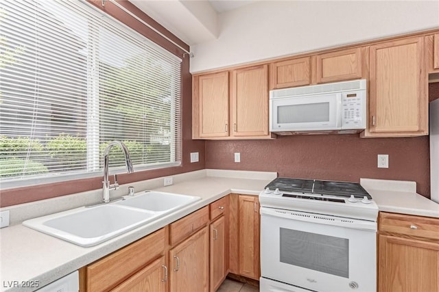 kitchen featuring white appliances, a sink, light brown cabinets, and light countertops