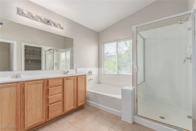 bathroom with vaulted ceiling, tile patterned floors, a stall shower, a garden tub, and double vanity