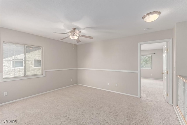 carpeted spare room with ceiling fan and baseboards
