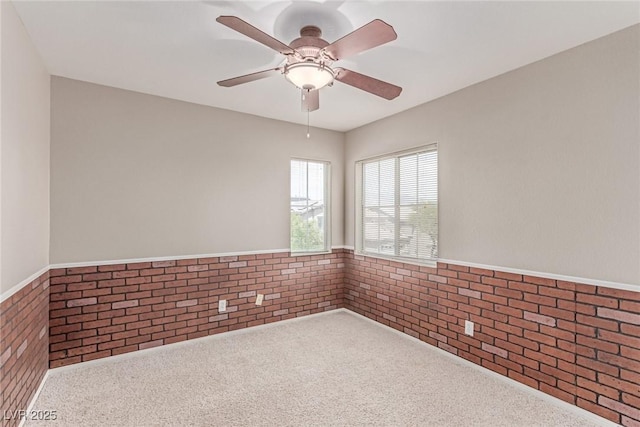 carpeted empty room with a wainscoted wall and a ceiling fan
