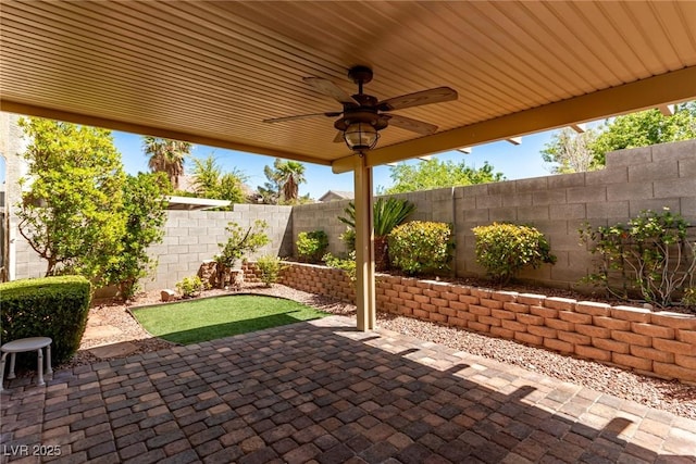 view of patio featuring a ceiling fan, a fenced backyard, and a putting green
