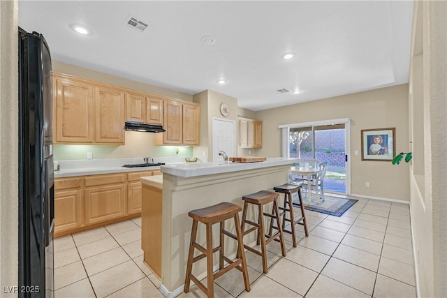 2309 Tedesca Dr, Henderson, NV 89052 - kitchen with light brown cabinets, light countertops, black refrigerator with ice dispenser, under cabinet range hood, and recessed lighting