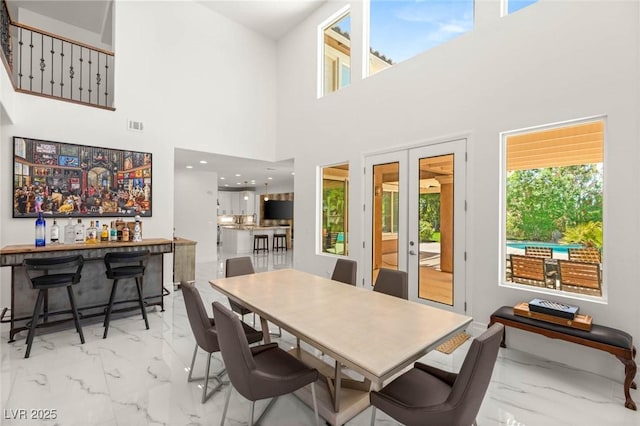 2940 Cimini Ct, Henderson, NV 89052 - dining area featuring marble look tile flooring, french doors, a bar, and a towering ceiling