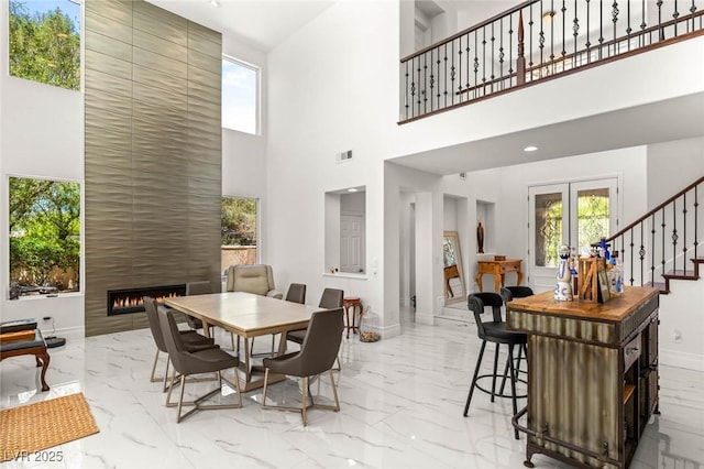 2940 Cimini Ct, Henderson, NV 89052 - dining area featuring marble tiled floors, a towering ceiling, a fireplace, stairs, and baseboards
