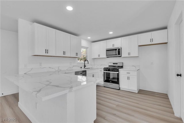 4186 Toronto Cir, Las Vegas, NV 89121 - kitchen featuring stainless steel appliances, a peninsula, light stone counters, a sink, and white cabinetry