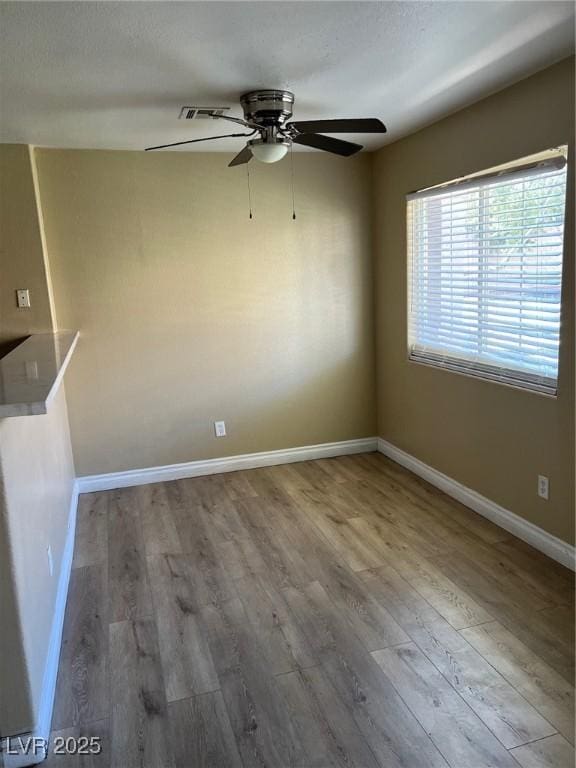 empty room featuring wood finished floors, ceiling fan, and baseboards
