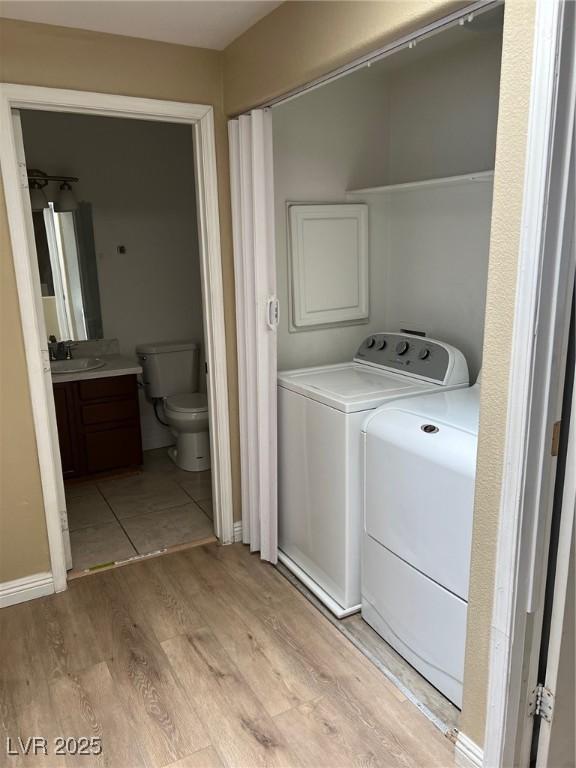 clothes washing area featuring washer and dryer and light wood-style floors