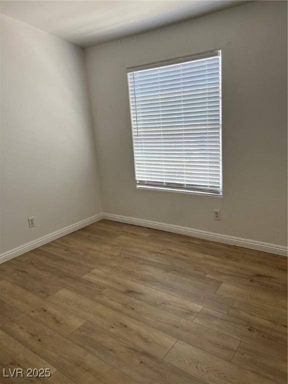 spare room featuring wood finished floors and baseboards