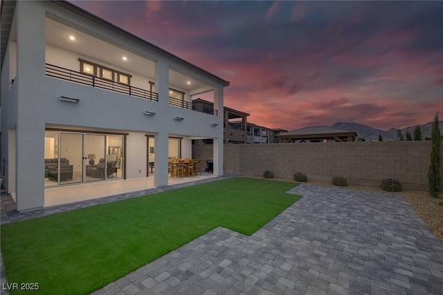 rear view of property featuring a balcony, a patio, and stucco siding