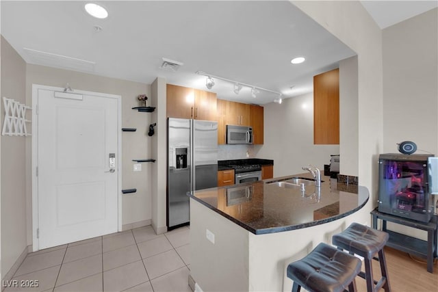 200 W Sahara Ave Unit 603, Las Vegas, NV 89102 - kitchen with stainless steel appliances, a sink, a peninsula, brown cabinets, and a kitchen breakfast bar