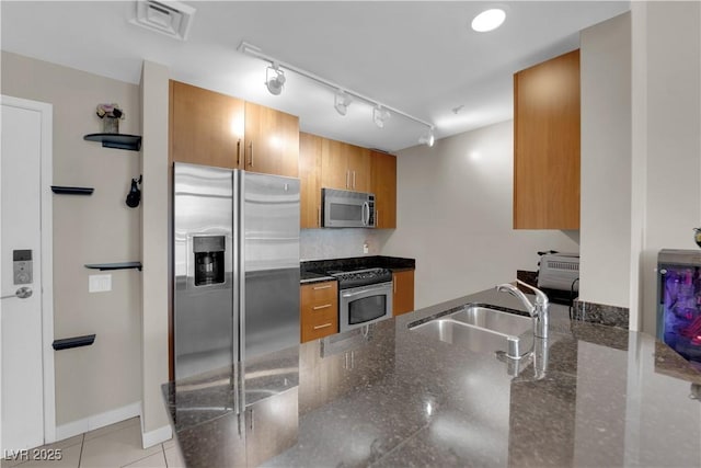 200 W Sahara Ave Unit 603, Las Vegas, NV 89102 - kitchen featuring stainless steel appliances, a sink, brown cabinetry, dark stone counters, and track lighting