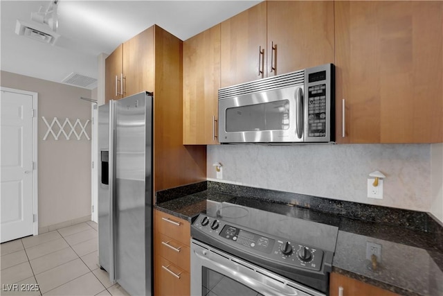200 W Sahara Ave Unit 603, Las Vegas, NV 89102 - kitchen featuring stainless steel appliances, brown cabinetry, dark stone counters, and light tile patterned flooring