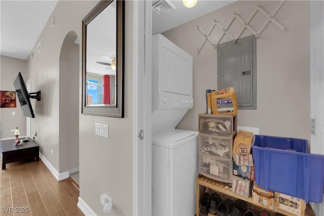 200 W Sahara Ave Unit 603, Las Vegas, NV 89102 - clothes washing area with stacked washing machine and dryer, electric panel, wood finished floors, baseboards, and arched walkways