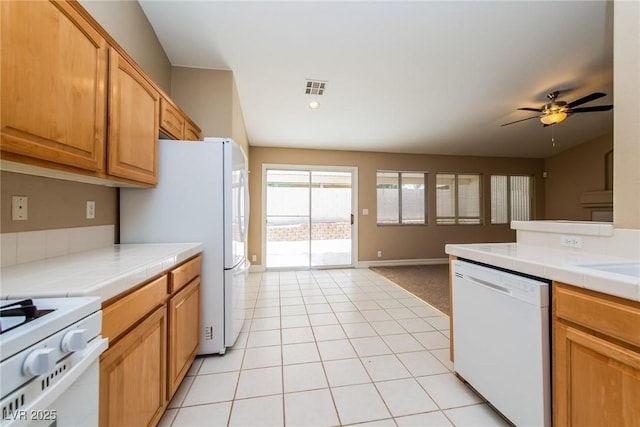 8205 Harrogate Ave, Las Vegas, NV 89129 - kitchen featuring white appliances, tile counters, ceiling fan, and light tile patterned flooring