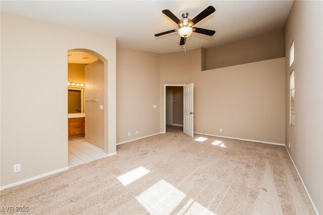 8205 Harrogate Ave, Las Vegas, NV 89129 - unfurnished bedroom with arched walkways, light colored carpet, baseboards, ensuite bathroom, and a high ceiling