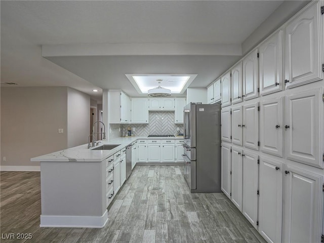 5452 Big Sky Ln, Las Vegas, NV 89149 - kitchen with stainless steel appliances, a sink, a peninsula, white cabinetry, and light wood-style floors