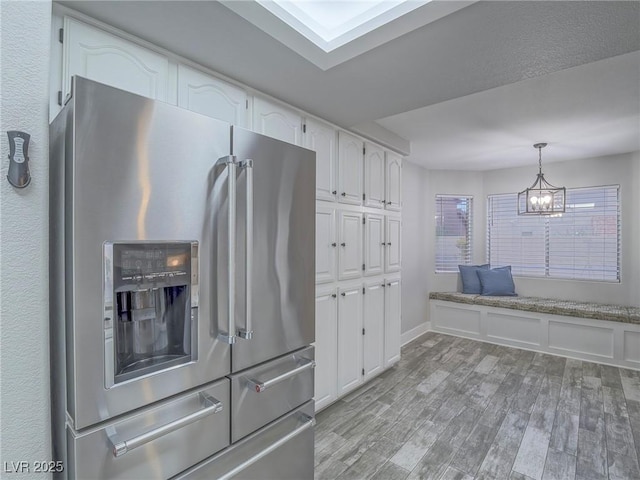5452 Big Sky Ln, Las Vegas, NV 89149 - kitchen with stainless steel refrigerator with ice dispenser, white cabinets, light wood-style floors, pendant lighting, and a chandelier