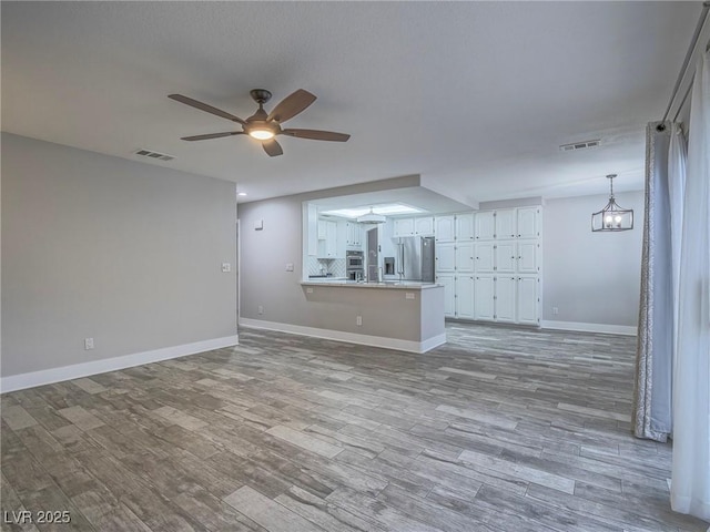 5452 Big Sky Ln, Las Vegas, NV 89149 - unfurnished living room with a ceiling fan, baseboards, wood finished floors, and a chandelier