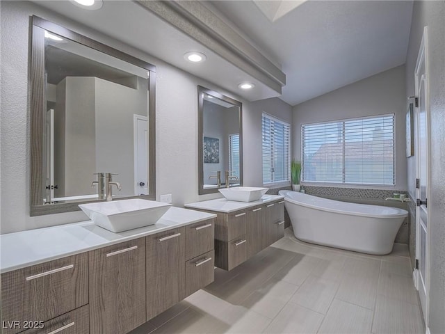5452 Big Sky Ln, Las Vegas, NV 89149 - bathroom with lofted ceiling, two vanities, a freestanding bath, and recessed lighting