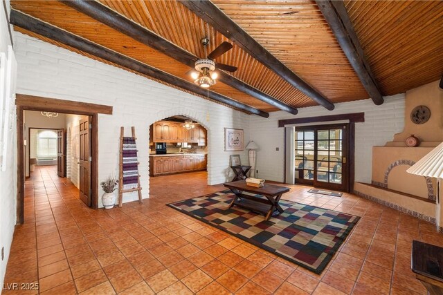 1320 Daytona St, Pahrump, NV 89048 - living room with light tile patterned floors, beamed ceiling, arched walkways, ceiling fan, and wooden ceiling