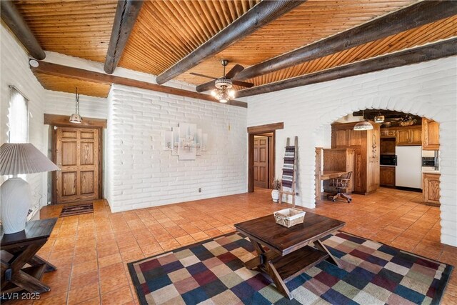 1320 Daytona St, Pahrump, NV 89048 - living room featuring light tile patterned flooring, ceiling fan, beam ceiling, wooden ceiling, and brick wall