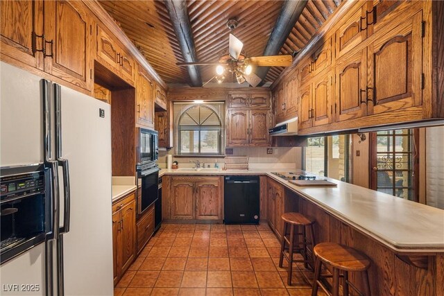 1320 Daytona St, Pahrump, NV 89048 - kitchen with black appliances, a peninsula, a ceiling fan, wooden ceiling, and light countertops