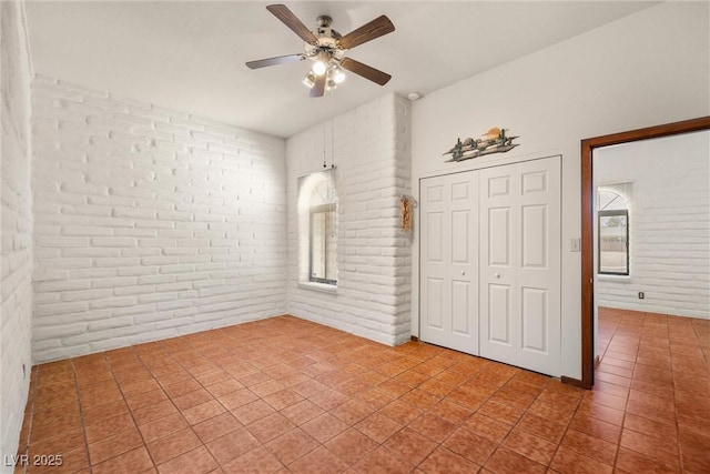 1320 Daytona St, Pahrump, NV 89048 - unfurnished bedroom featuring brick wall, a closet, tile patterned floors, and a ceiling fan