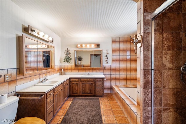 1320 Daytona St, Pahrump, NV 89048 - bathroom featuring tile walls, toilet, tile patterned floors, a relaxing tiled tub, and double vanity
