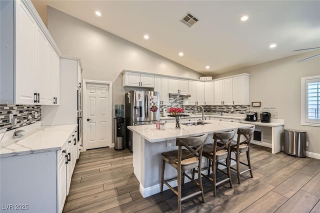 5638 Wild Olive St, Las Vegas, NV 89118 - kitchen featuring a sink, stainless steel fridge, wood finished floors, decorative backsplash, and light stone counters