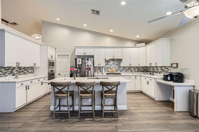 5638 Wild Olive St, Las Vegas, NV 89118 - kitchen with stainless steel appliances, a sink, lofted ceiling, tasteful backsplash, and a center island with sink