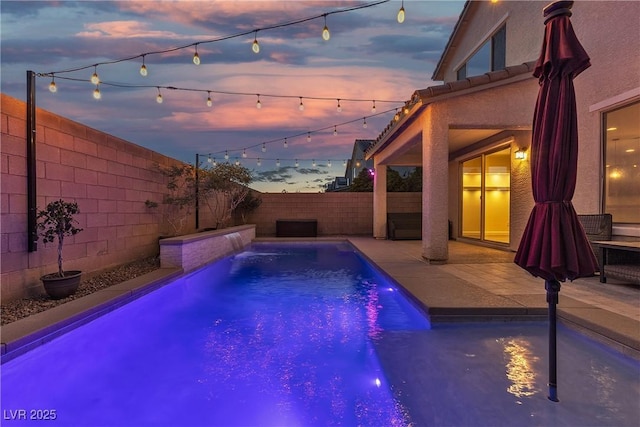 pool at dusk with a fenced backyard and a patio area