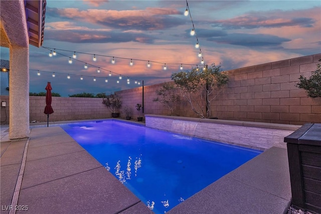 pool at dusk featuring a fenced backyard and a patio area