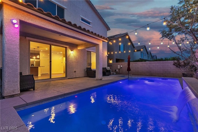 pool at dusk featuring a patio and a fenced backyard