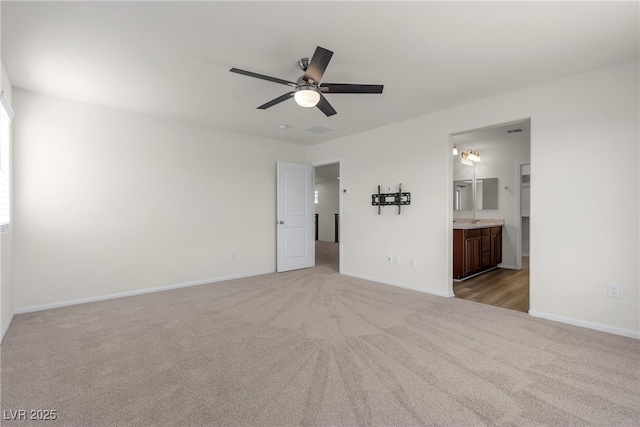 unfurnished bedroom with light colored carpet, baseboards, connected bathroom, and ceiling fan
