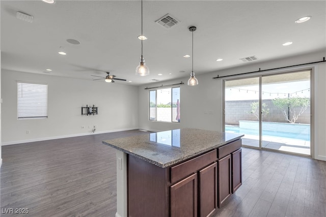 kitchen featuring dark wood-style floors, recessed lighting, pendant lighting, ceiling fan, and light stone counters