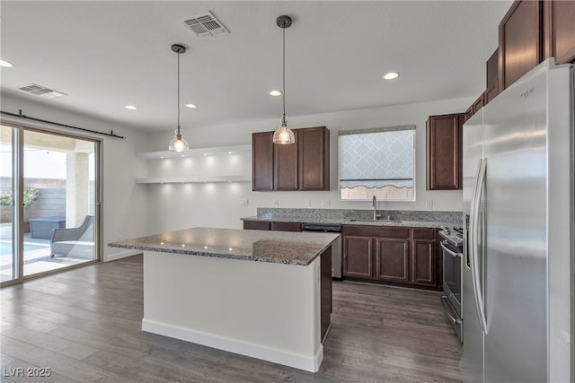 kitchen with appliances with stainless steel finishes, a sink, dark wood-style flooring, stone countertops, and recessed lighting