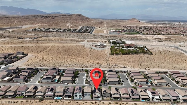 aerial view of property and surrounding area featuring mountains, a desert landscape, and nearby suburban area