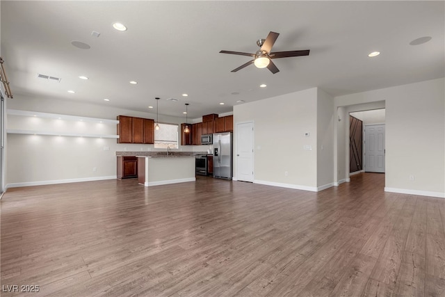 unfurnished living room with a ceiling fan, wood finished floors, a sink, baseboards, and recessed lighting