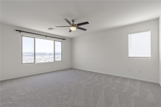 spare room with a ceiling fan, light colored carpet, and baseboards