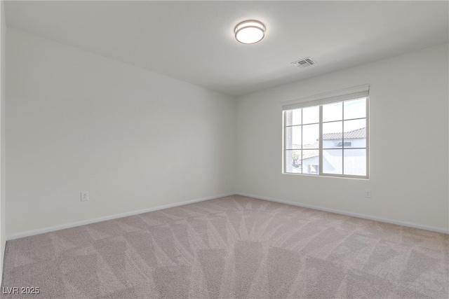 spare room with light carpet and baseboards