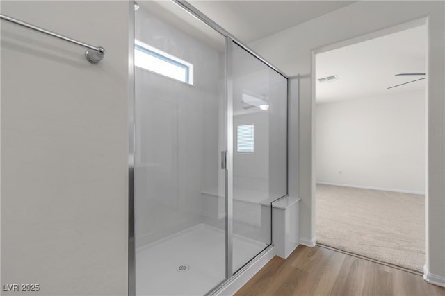 bathroom featuring a shower with shower door, baseboards, and wood finished floors