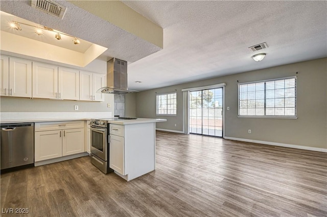 1620 Yellow Rose St, Las Vegas, NV 89108 - kitchen with wall chimney range hood, appliances with stainless steel finishes, a textured ceiling, a peninsula, and open floor plan