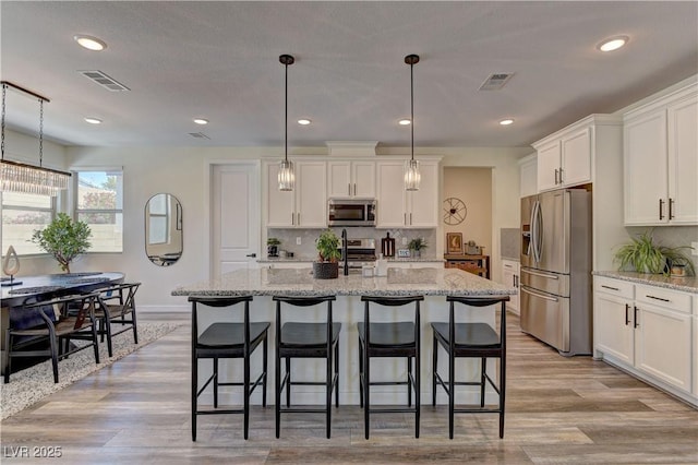 8335 Beaten Path Ct, Las Vegas, NV 89166 - kitchen featuring stainless steel appliances, light wood-style flooring, white cabinetry, a breakfast bar area, and recessed lighting