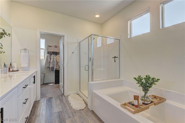 8335 Beaten Path Ct, Las Vegas, NV 89166 - bathroom with wood finished floors, a shower stall, a spacious closet, a garden tub, and vanity