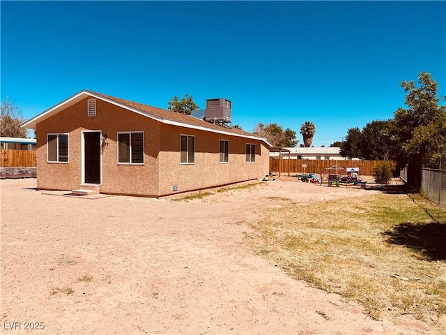rear view of property featuring a fenced backyard, stucco siding, and central air condition unit
