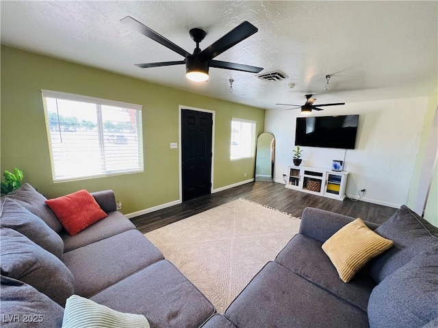 living area featuring a ceiling fan, wood finished floors, baseboards, and a textured ceiling