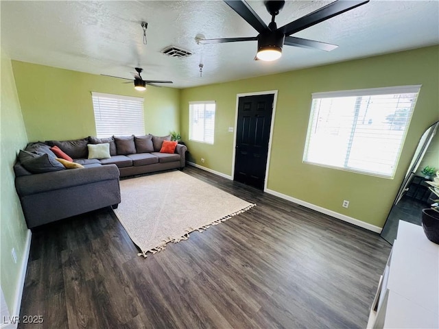 living area with ceiling fan, baseboards, dark wood finished floors, and a textured ceiling