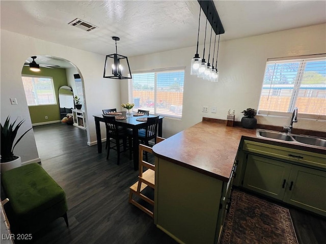 kitchen featuring dark wood-style flooring, arched walkways, a sink, and healthy amount of natural light