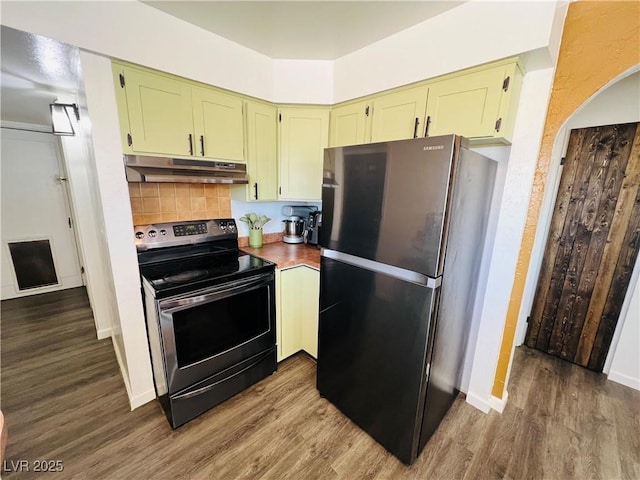 kitchen featuring stainless steel electric stove, under cabinet range hood, freestanding refrigerator, green cabinets, and dark wood-style floors