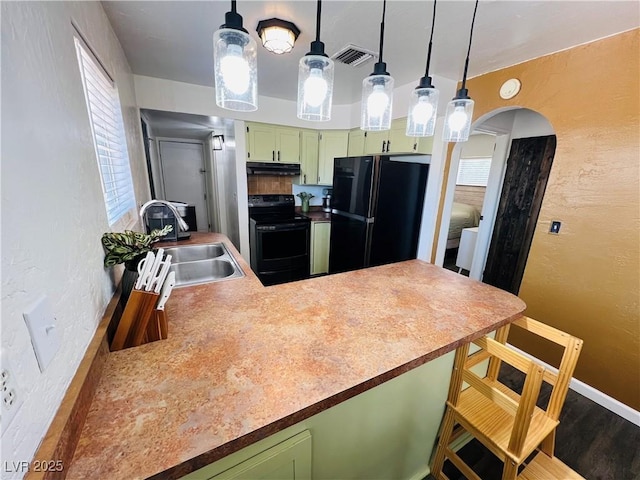 kitchen featuring black appliances, green cabinetry, a sink, under cabinet range hood, and a textured wall